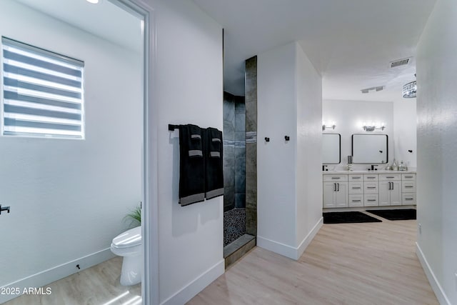3903 E Melody Dr, Phoenix, AZ 85042 - bathroom featuring double vanity, toilet, a walk in shower, wood finished floors, and baseboards