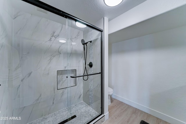 3903 E Melody Dr, Phoenix, AZ 85042 - full bathroom featuring toilet, a marble finish shower, wood finished floors, baseboards, and a textured ceiling