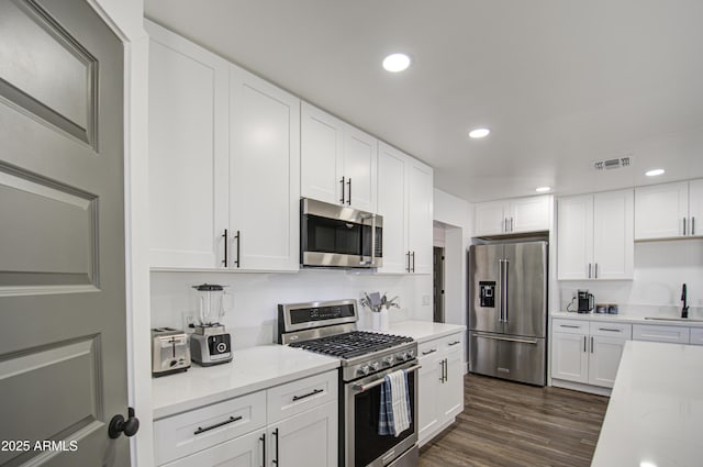 kitchen featuring sink, dark wood-type flooring, white cabinetry, stainless steel appliances, and light stone countertops