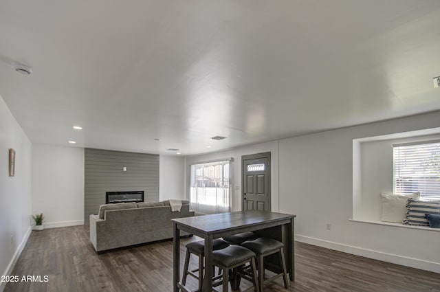 dining space with a large fireplace, plenty of natural light, and dark hardwood / wood-style flooring