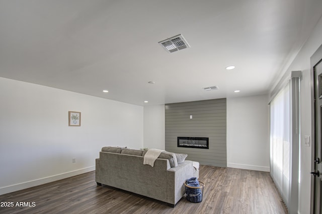 living room featuring a large fireplace and dark hardwood / wood-style flooring