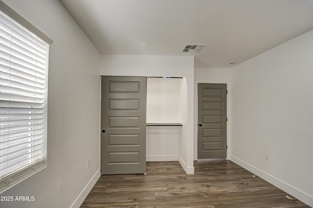 unfurnished bedroom with dark hardwood / wood-style floors and a closet