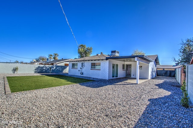 rear view of property featuring a yard, central AC unit, and a patio area