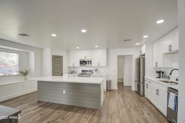 kitchen with stainless steel appliances, a center island, sink, and white cabinets