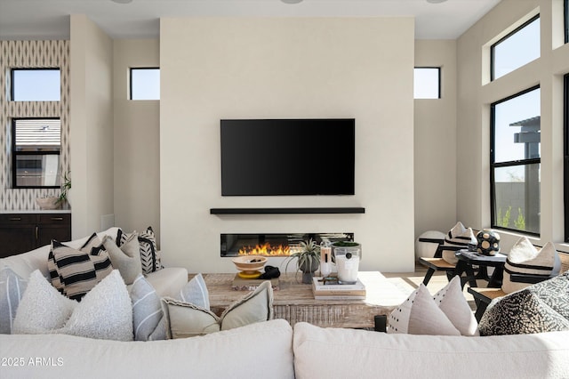 living room featuring a high ceiling and a glass covered fireplace