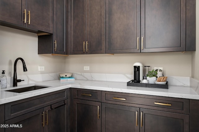 kitchen featuring a sink, dark brown cabinetry, and light stone countertops