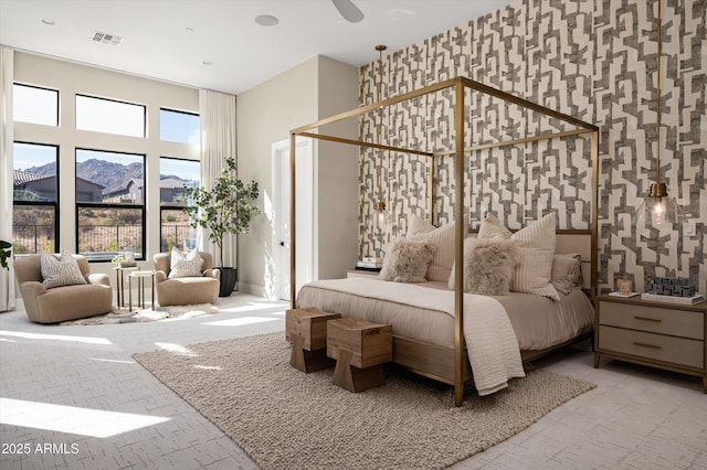 bedroom with a mountain view, brick floor, visible vents, and wallpapered walls