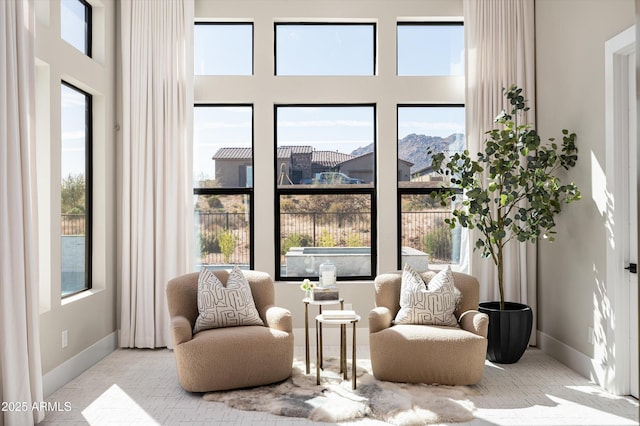 living area featuring a high ceiling, a mountain view, and baseboards