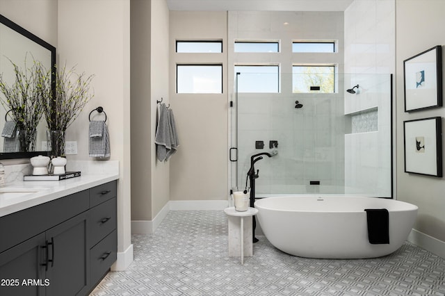 bathroom featuring baseboards, a healthy amount of sunlight, a shower stall, and vanity