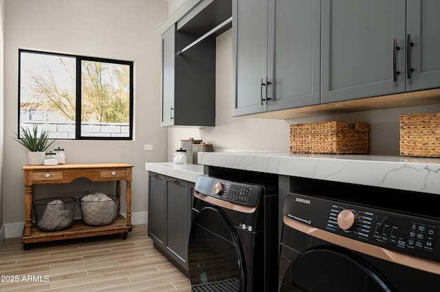 washroom featuring washer and dryer, cabinet space, baseboards, and wood tiled floor