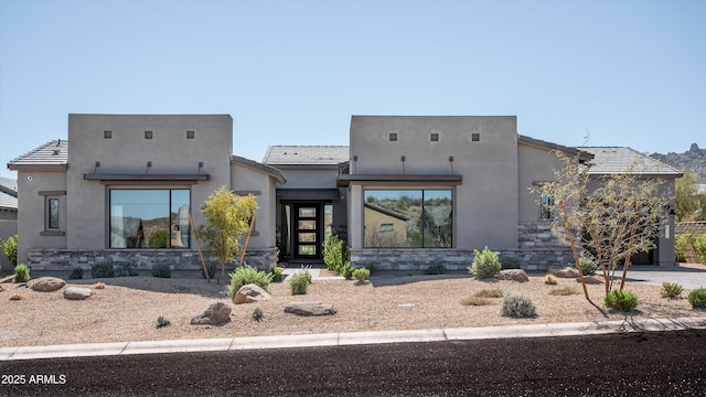 pueblo revival-style home with stone siding and stucco siding