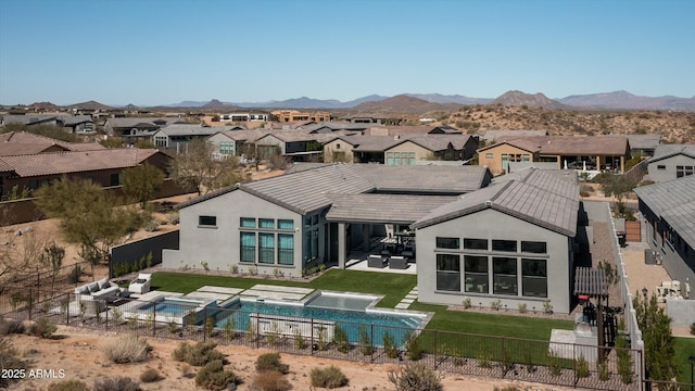 back of property with stucco siding, a fenced backyard, a yard, and a mountain view