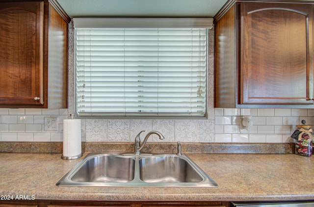 kitchen featuring stainless steel dishwasher, sink, and backsplash