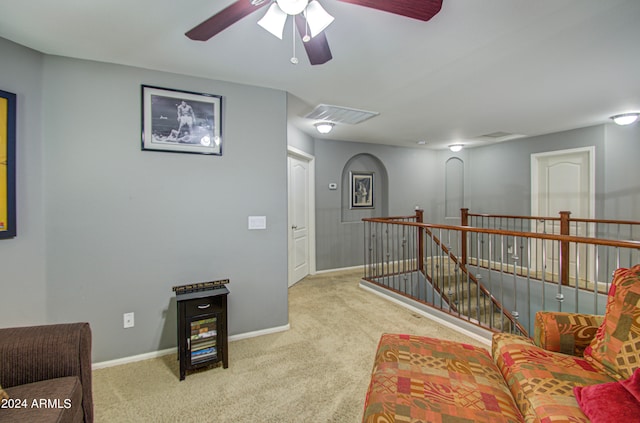 living area featuring light colored carpet and ceiling fan