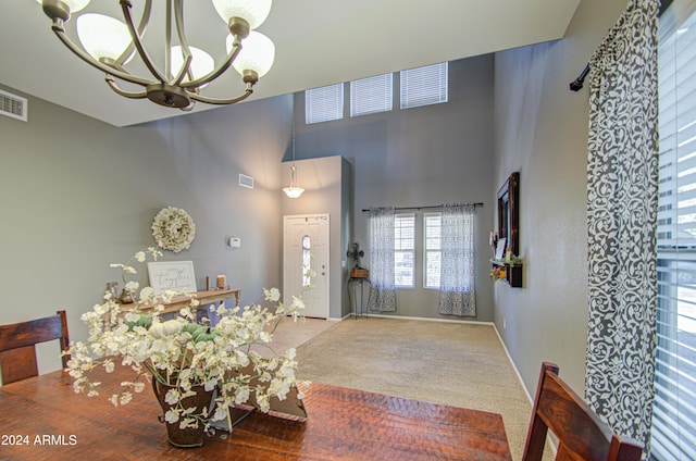 carpeted dining room featuring a towering ceiling and an inviting chandelier