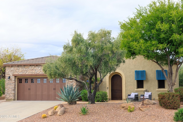 view of front facade featuring stone siding, stucco siding, driveway, and an attached garage