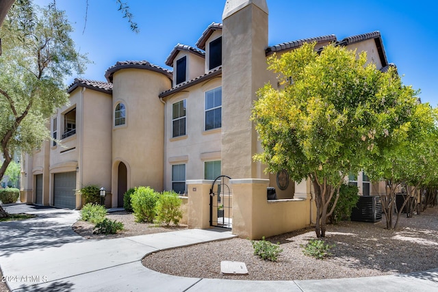 mediterranean / spanish home featuring a chimney, stucco siding, fence, a garage, and driveway