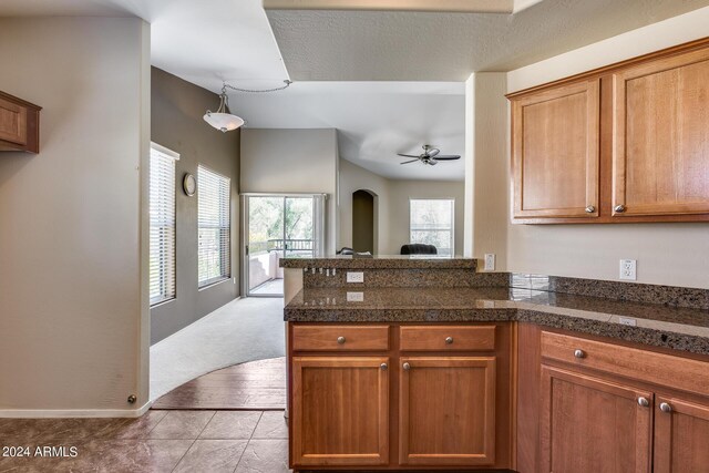 kitchen featuring tile countertops, ceiling fan, a peninsula, tile patterned floors, and brown cabinetry