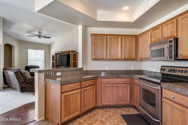 kitchen featuring tile countertops, arched walkways, stainless steel appliances, a peninsula, and open floor plan