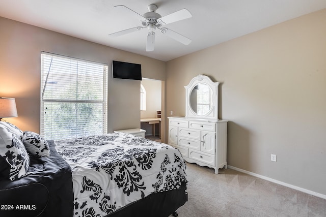 bedroom featuring ceiling fan, ensuite bathroom, and light colored carpet