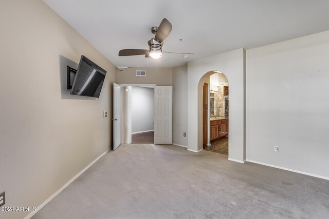 empty room featuring visible vents, arched walkways, baseboards, ceiling fan, and carpet floors