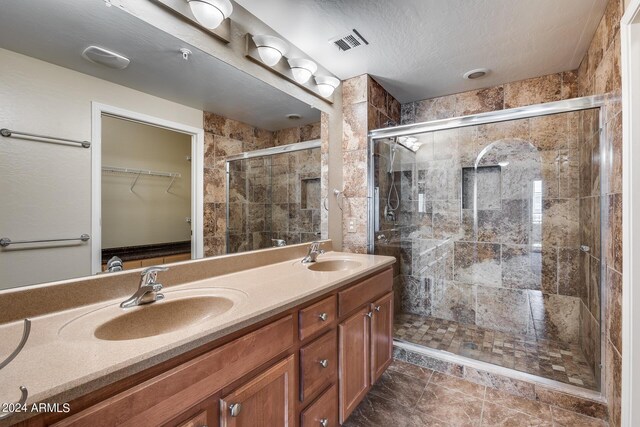 bathroom with double vanity, a sink, visible vents, and a shower stall