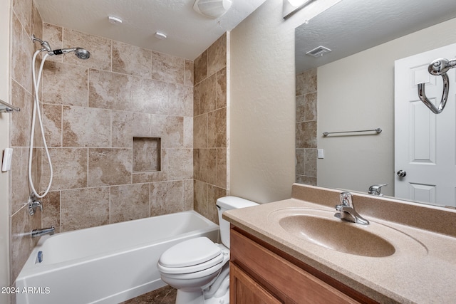 full bathroom with a textured ceiling, vanity, tiled shower / bath, and toilet