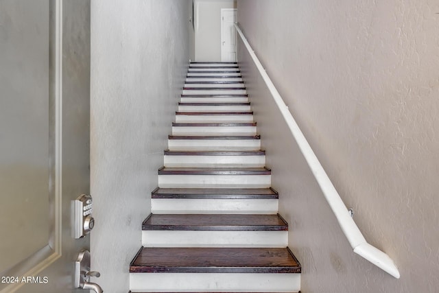 stairway featuring a textured wall