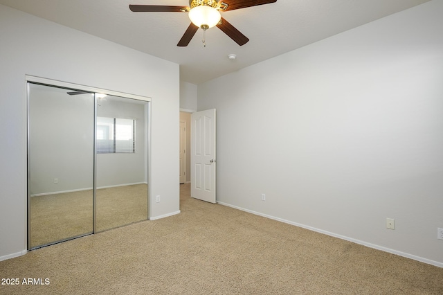 unfurnished bedroom with ceiling fan, a closet, and light carpet