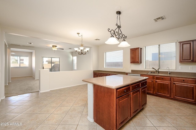 kitchen with ceiling fan with notable chandelier, sink, decorative light fixtures, a kitchen island, and light tile patterned flooring