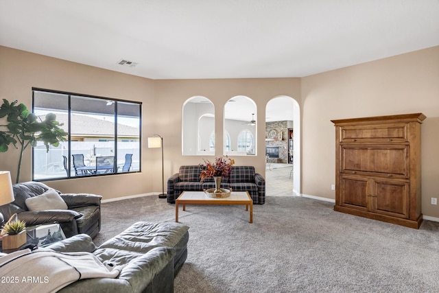 living area with arched walkways, carpet floors, a fireplace, and baseboards