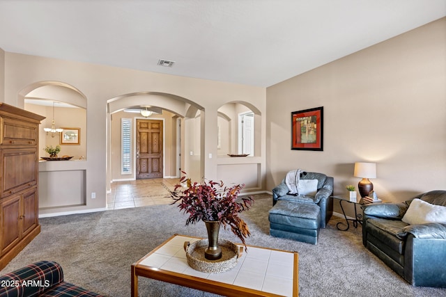 living room with light tile patterned floors, arched walkways, light carpet, visible vents, and baseboards