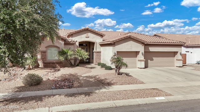 mediterranean / spanish home featuring concrete driveway, an attached garage, a tiled roof, and stucco siding