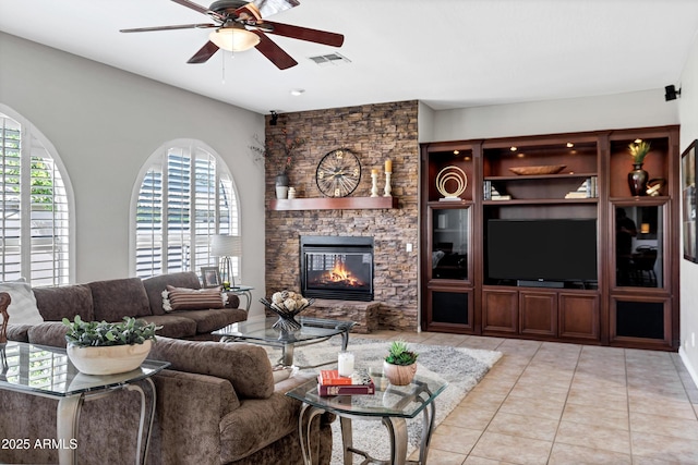 living area featuring light tile patterned floors, ceiling fan, a fireplace, and visible vents