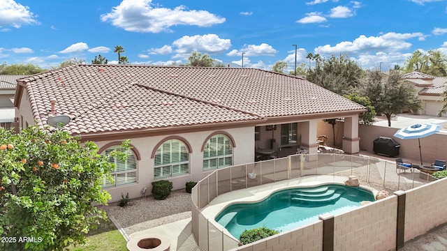 rear view of property featuring a tile roof, a patio, a fenced backyard, and stucco siding