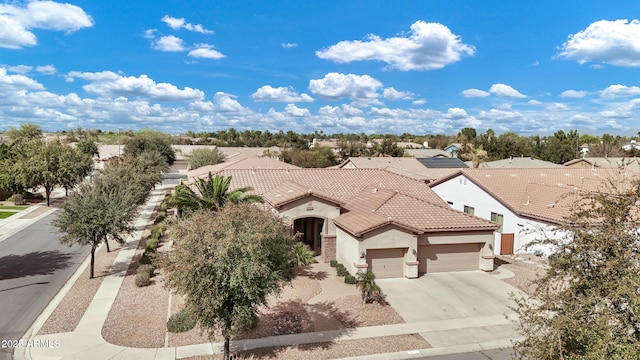 view of front facade featuring a tile roof, driveway, an attached garage, and stucco siding