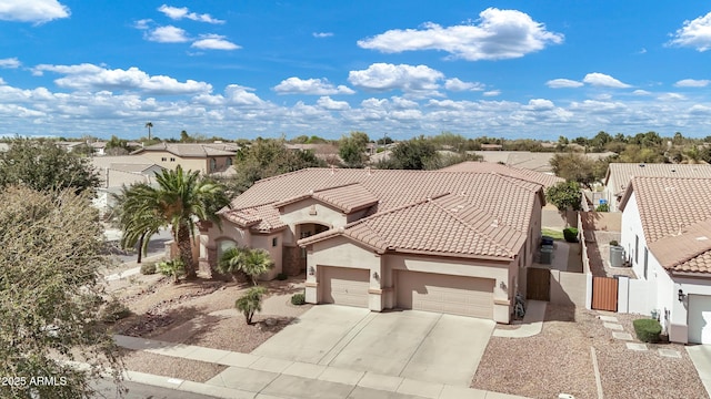 mediterranean / spanish home with a tile roof, stucco siding, an attached garage, fence, and driveway