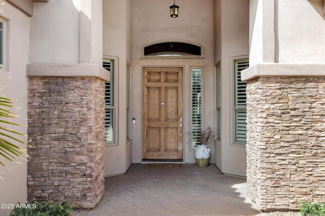 property entrance featuring stone siding and stucco siding