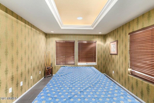 unfurnished bedroom with a tray ceiling, ornamental molding, and tile patterned floors