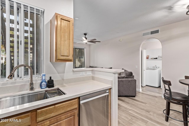 kitchen with sink, dishwasher, ceiling fan, light hardwood / wood-style floors, and washer / dryer