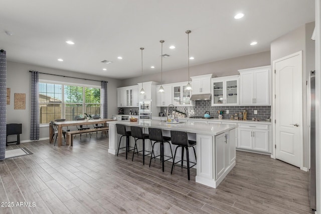 1342 E Milada Dr, Phoenix, AZ 85042 - kitchen with a spacious island, light wood-type flooring, appliances with stainless steel finishes, light countertops, and under cabinet range hood