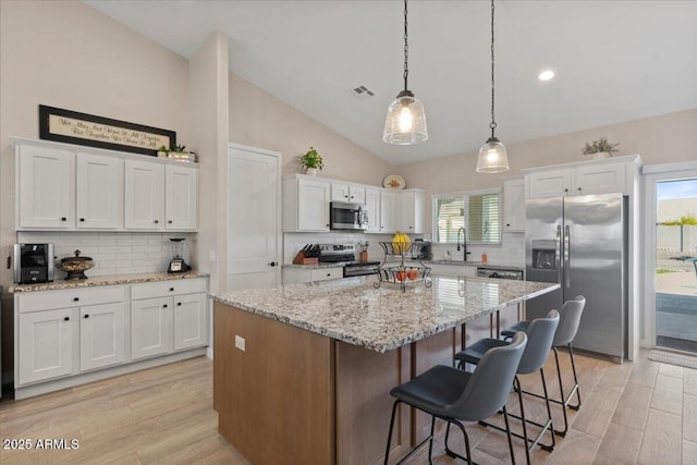 kitchen with visible vents, vaulted ceiling, light wood-style flooring, stainless steel appliances, and white cabinetry