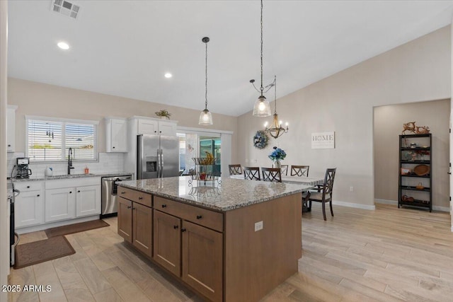 kitchen with visible vents, a center island, lofted ceiling, appliances with stainless steel finishes, and a sink