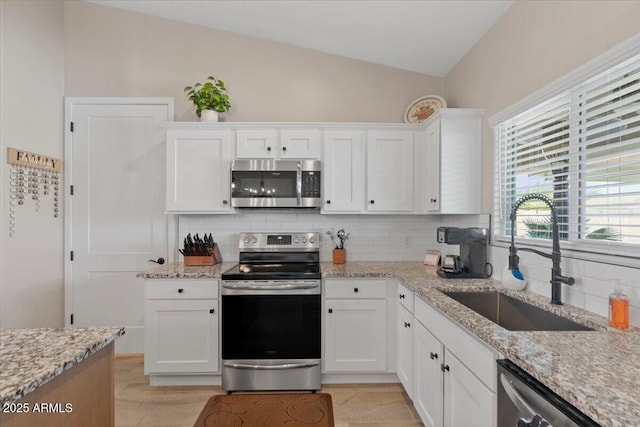 kitchen featuring decorative backsplash, appliances with stainless steel finishes, white cabinetry, and a sink