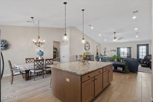 kitchen featuring light stone counters, visible vents, lofted ceiling, light wood-type flooring, and a center island