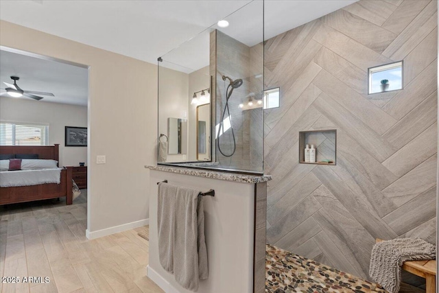 ensuite bathroom featuring wood finished floors, connected bathroom, baseboards, walk in shower, and ceiling fan