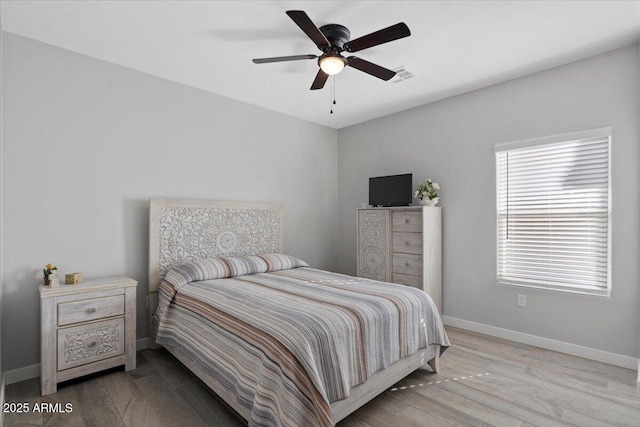 bedroom with visible vents, a ceiling fan, baseboards, and wood finished floors