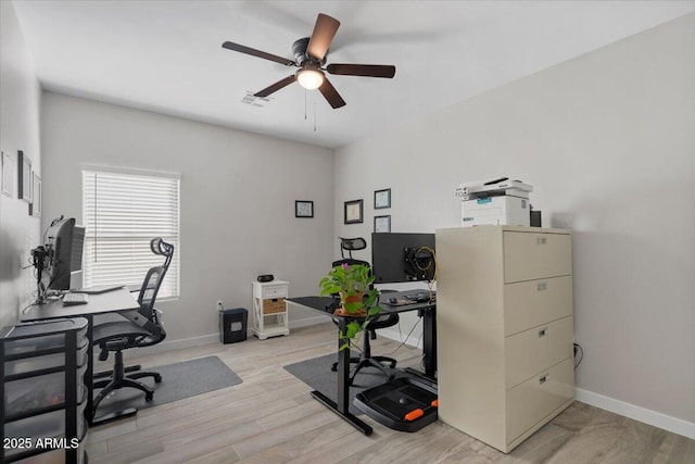 home office featuring visible vents, baseboards, light wood-style flooring, and a ceiling fan