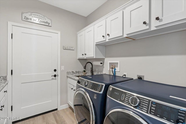 washroom featuring light wood finished floors, cabinet space, separate washer and dryer, and a sink