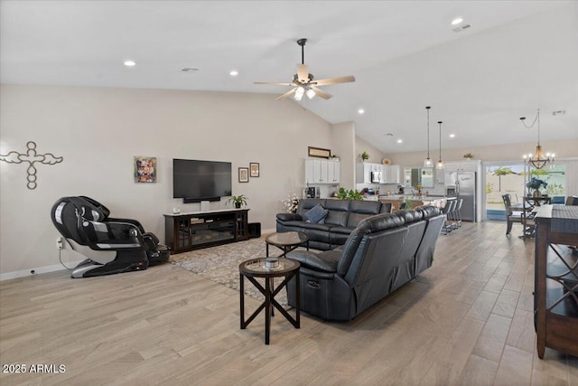 living area featuring light wood finished floors, ceiling fan with notable chandelier, high vaulted ceiling, and baseboards